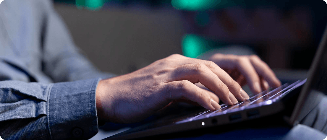 Close-up of hands typing on a backlit laptop keyboard