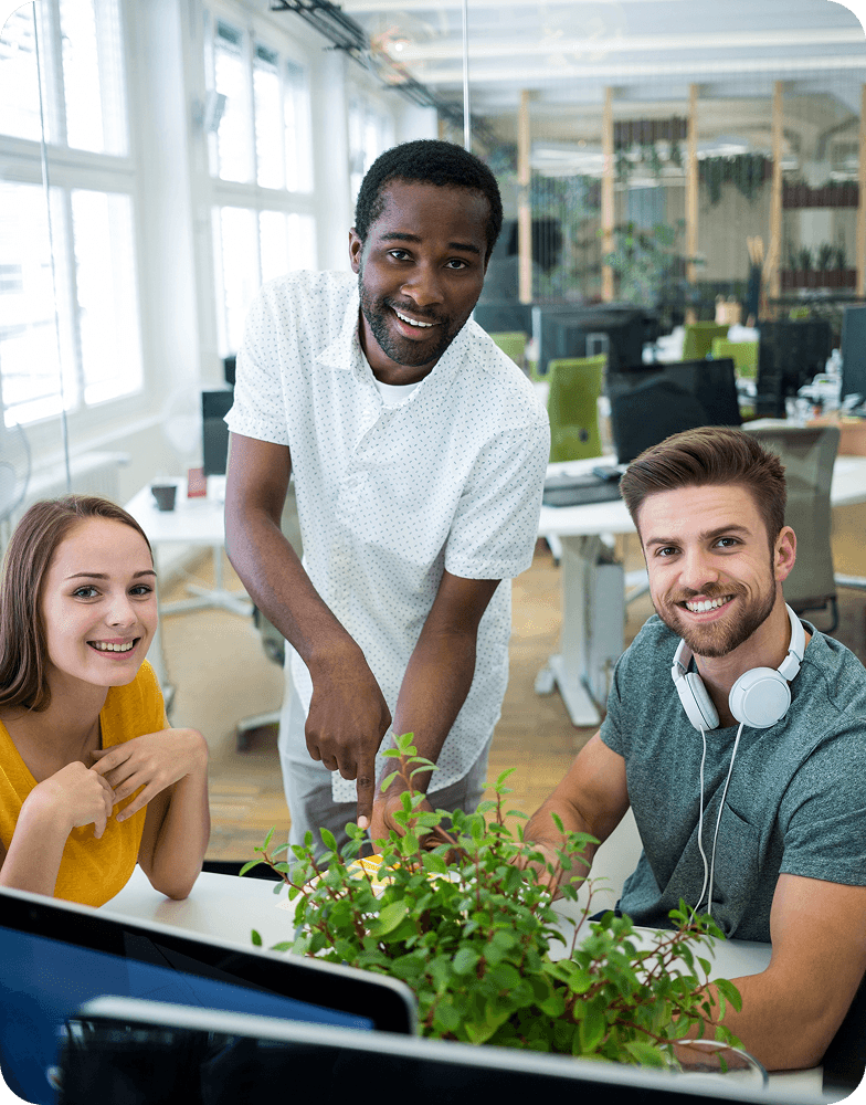Three teammates smiling around a desk in a bright office